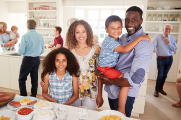 Portrait Of Family With Friends In Kitchen For Multi-Generation Party