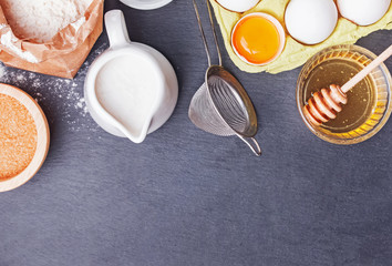 Baking ingredients and tools on the black stone background
