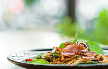 delicious spicy spaghetti dried chilli and basil sauce with bacon and mushroom ,beautiful close up spicy spaghetti bacon on black plate with some space for text.
