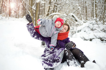 Fototapeta na wymiar Woman playing with a child in the snow in the park
