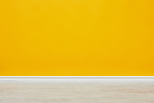 background of bright empty yellow wall with wooden floor