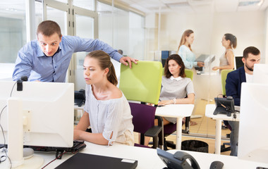 Businessman helping female colleague in work with computer