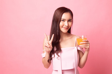 Healthy young Asian woman with  orange  juice on pink background