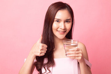 Healthy young Asian woman thumb up with  water on pink background