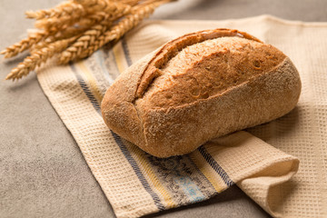 Grain bread with seeds and crunchy fragrant crust is on a towel.