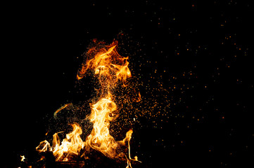 Burning woods with firesparks, flame and smoke. Strange weird odd elemental fiery figures on black background. Coal and ash. Abstract shapes at night. Bonfire outdoor on nature. Strenght of element.