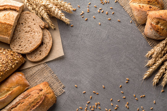 Bread Background With Wheat, Aromatic Crispbread With Grains, Copy Space, Top View. Brown And White Whole Grain Loaves Still Life Composition With Wheat Ears Scattered Around.