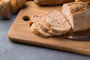 Sliced bread on the grey stone table, knife, close up.