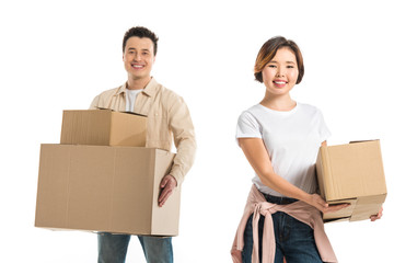 happy couple looking at camera and holding cardboard boxes isolated on white, moving to new house concept