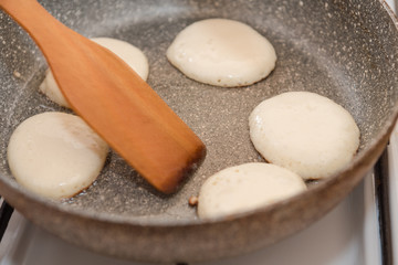 Fry fritters at home in the pan. Cooking pastries. Stand near the stove. View from above.