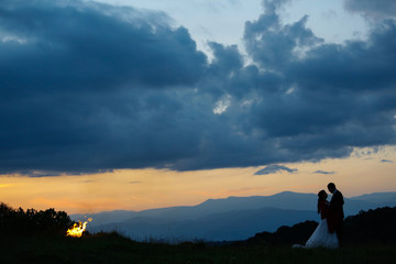 Fototapeta premium Beautiful wedding couple posing in nature with fire