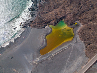 Vista aerea del piccolo lago sotto la montagna Bermeja, vista della spiaggia nera e della strada...