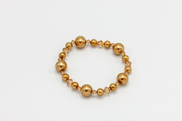 gold colored and multiple sized beads bracelet on white background