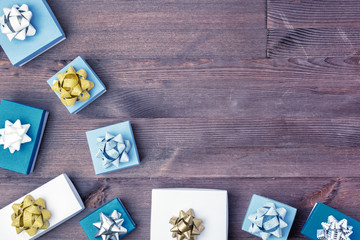 Copy space on wooden background. Christmas composition, white and blue gift boxes decorated with gold and silver bows. Festive layout.