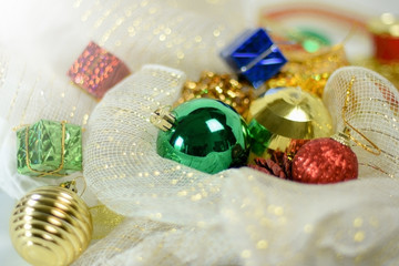 Variety of color decoration balls and items for Christmas tree with soft ribbon wrap as background.