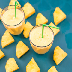 Pineapple smoothie with fresh pineapple on wooden blue table.