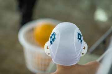 player and teammate on a water field. teammates with white hats, water sports enthusiasts sit outside the pool. © Ivan