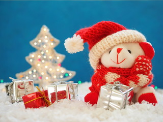Cute white bear in red hat of Santa Claus, gift boxes and shining fir tree 