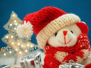 Cute white bear in red hat of Santa Claus, gift boxes and shining fir tree 