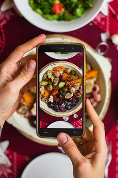 Phone food photography. Woman hands take a photo of lunch or dinner with smartphone for social networks or blogging in trendy top view style. Mobile phone screen. Vegan vegetarian healthy food