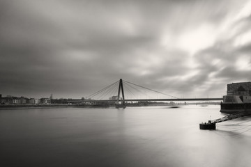 Blick auf die Severinsbrücke und den Rhein in schwarzweiß und Langzeitbelichtung.