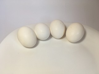 White eggs on a white plate on a white background. The birth of life. 4 Chicken eggs.