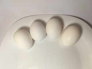 White eggs on a white plate on a white background. The birth of life. 4 Chicken eggs.