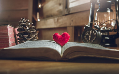 Open Bible with a red heart in the middle, on wooden table. concept for love of God