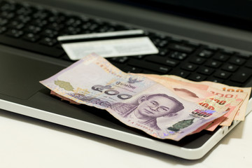 A blurred of  credit card, Thai currency 500 Baht and laptop after shopping on line, E-commerce net work marketing concept