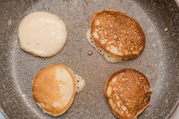 Fry fritters at home in the pan. Cooking pastries. Stand near the stove. View from above.
