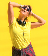 Portrait of happy beautiful blonde girl hold her wooden longboard skateboard on yellow background wall, look to the camera and smile. Urban scene, city life. Hipster cute lady.