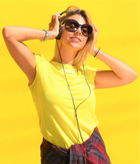 Portrait of happy beautiful blonde girl hold her wooden longboard skateboard on yellow background wall, look to the camera and smile. Urban scene, city life. Hipster cute lady.