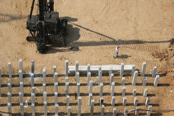 field piles at the construction site and a pile driver