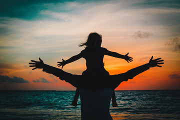 father and little daughter play at sunset sky