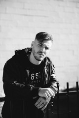 Handsome Brooding Young Man Posing in Leather Bomber Jacket Outside in the Sun 