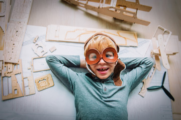happy little boy with helmet and glasses building toy plane