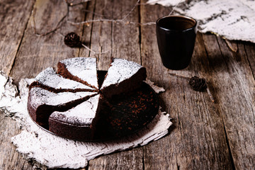 Kladdkaka. Traditional Swedish moist chocolate cake on old rustic wooden table decorated dry twigs, pine cones and birch bark. Fika. Hygge