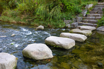 Big rocks are array as a path way to walk across the stream in the park.