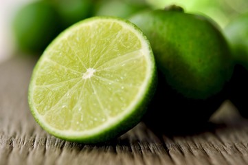 Fototapeta na wymiar limes slices on wooden table. Detox diet, fresh lime Background, Close up shot, fruit macro photography