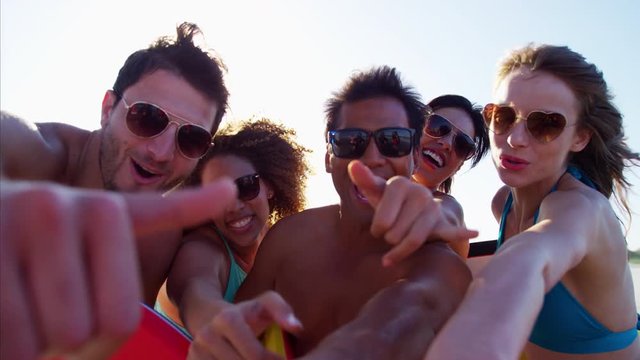 Happy multi ethnic friends in swimwear holding bodyboard on the beach