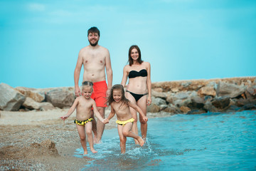 Happy family enjoying walk on the sea beach. The summer, childhood, holiday, leisure, lifestyle, travel, vacation concept