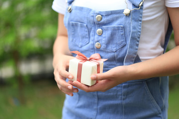 Selective focus of Woman hands holding yellow gift box with pink ribbon for Christmas and New Year's Day or Greeting season