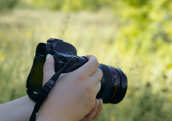 Fototapeta premium Image of female hands with a camera. Background, cropped shot, bokeh. Hobby concept