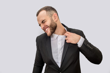 Young man in suit suffer. He holds edge of collar and pull it. Young man shrinks. Isolated on white background.