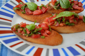 Traditional italian bruschetta with cherry tomatoes, cream cheese, basil leaves, capers and balsamic vinegar on plate. Close up view