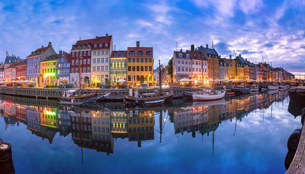 Panoramic view of Nyhavn with colorful facades of old houses and old ships in the Old Town of Copenhagen, capital of Denmark.