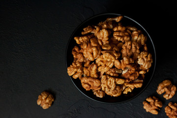 Walnut in a bowl on a black slate or stone background - healthy snack.Top view with copy space.