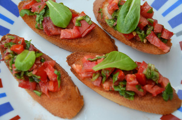 Traditional italian bruschetta with cherry tomatoes, cream cheese, basil leaves, capers and balsamic vinegar on plate. Close up view