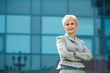 stylish modern aged woman in a summer suit against a blue building