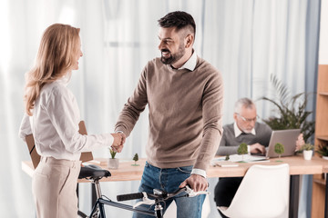 Glad woman shaking hands with her colleague